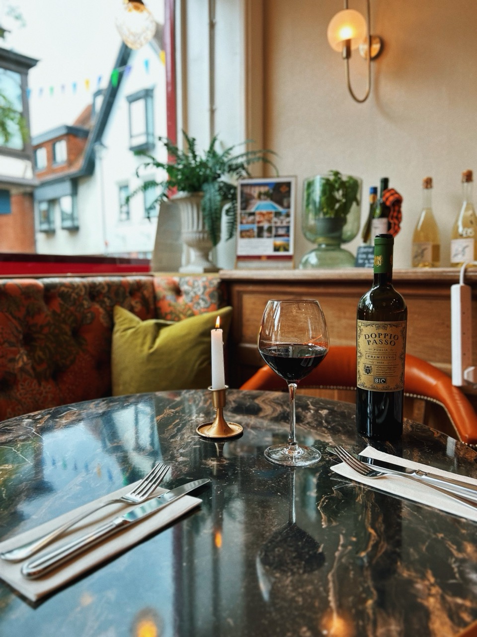 A candle and a glass of red wine on a marble table by the window at The Priory